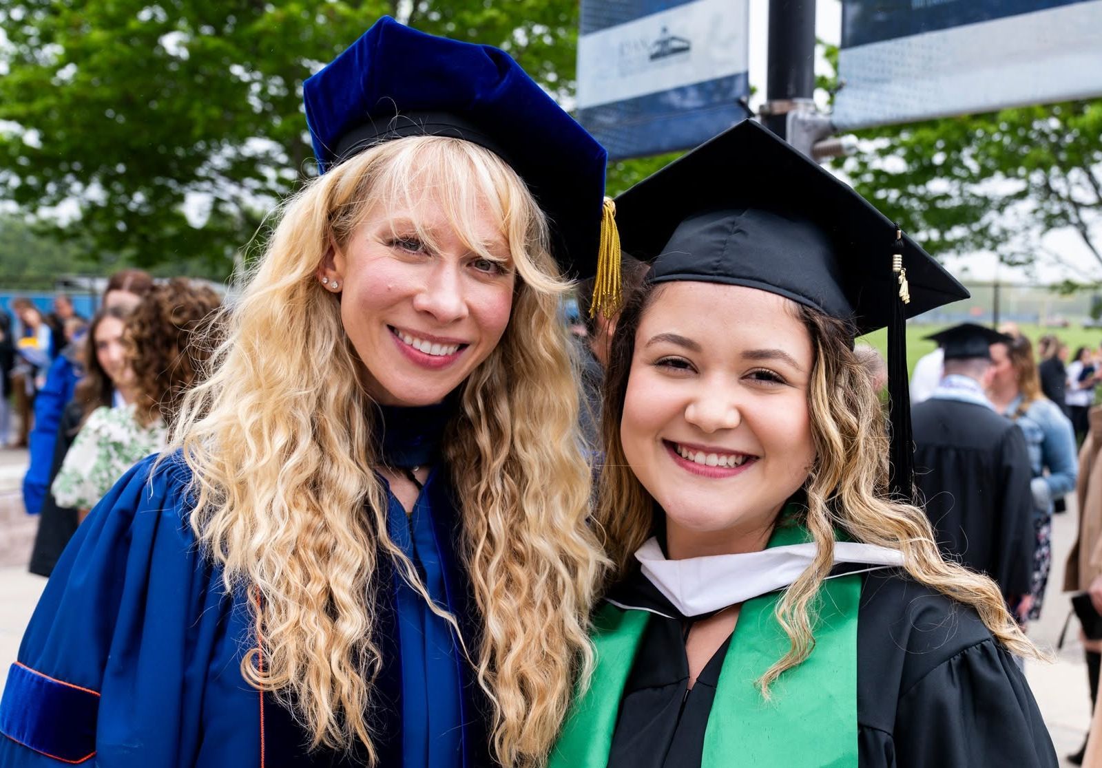 Ashlea Rundlett in doctoral regalia standing next to a master's graduate in cap and gown at a University of Rhode Island commencement.