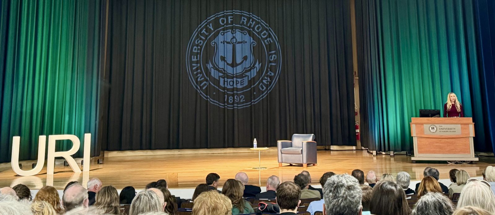 Ashlea Rundlett lecturing to a full auditorium at the University of Rhode Island.